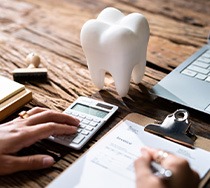Patient calculating cost on desk with laptop