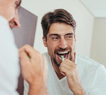 Man smiling while brushing his teeth