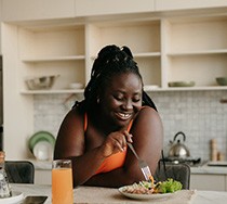 Woman smiling while eating lunch in kitchen
