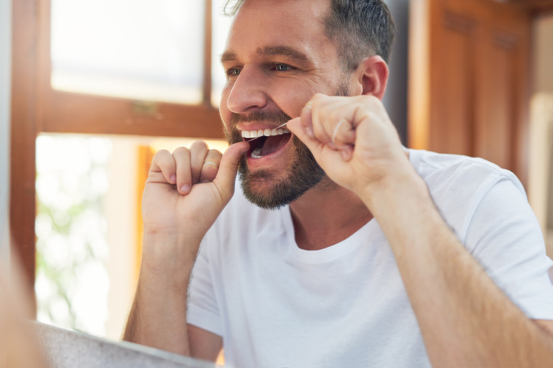 Patient flossing in their bathroom mirror